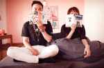 couple holding books sitting on bed